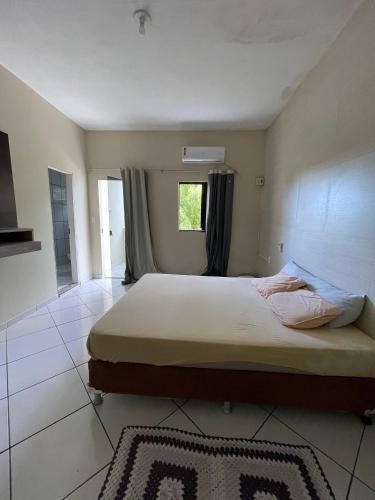 a bedroom with a large bed with a window at Imóvel amplo, bem ventilado e boa localização in Mucuri