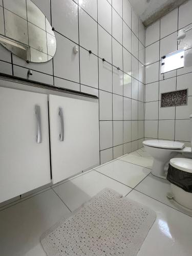 a white bathroom with a toilet and a sink at Imóvel amplo, bem ventilado e boa localização in Mucuri