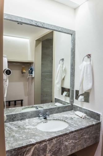 a bathroom with a sink and a large mirror at Hotel Guidi Linares in Linares