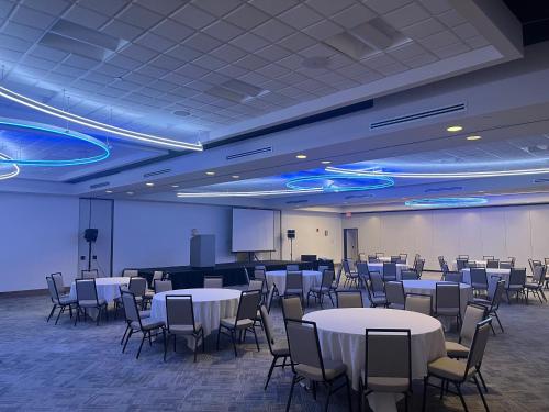 a conference room with tables and chairs and a screen at Holiday Inn Orlando International Airport by IHG in Orlando
