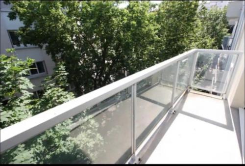 un balcon avec une balustrade en verre et un arbre dans l'établissement Cocon lumineux, à Vichy