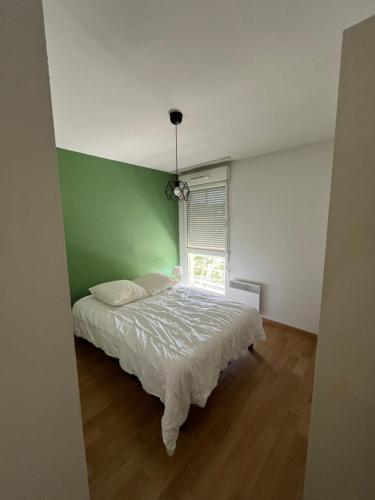 une chambre avec un lit blanc et un mur vert dans l'établissement Cocon lumineux, à Vichy