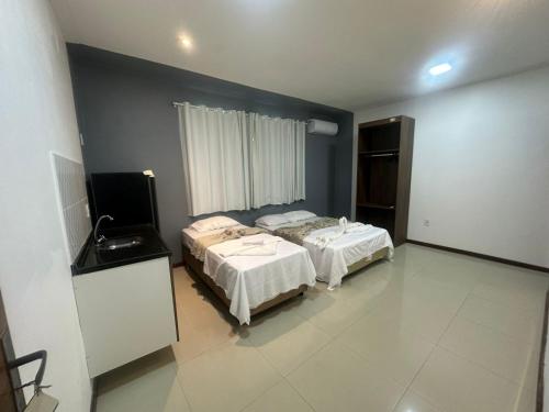 a bedroom with two beds and a flat screen tv at Pousada Aroeira in Arraial do Cabo