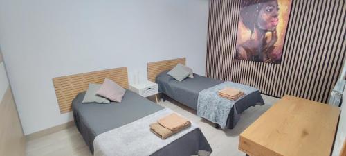 a room with two beds and a table and a painting at Casa Fausto Lasarte-oria in Lasarte