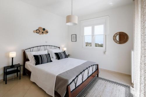 a white bedroom with a bed and a window at La Hacienda cozy home in Pigi