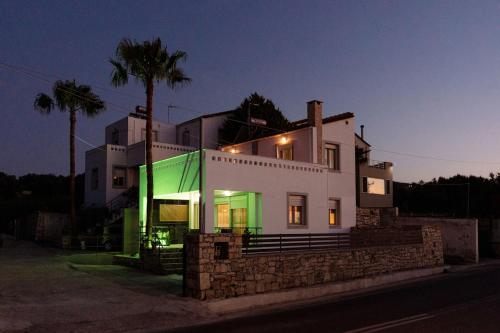a large white house with a green facade at night at La Hacienda cozy home in Pigi
