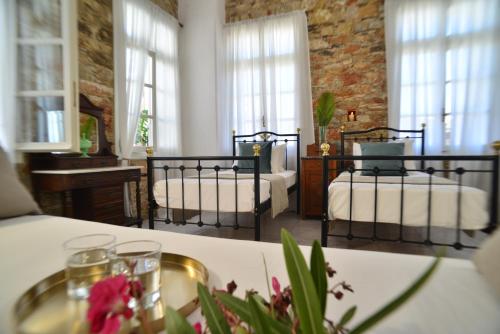 a bedroom with two beds in a room with windows at Axilleion Boutique Hotel in Ermoupoli