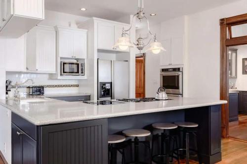 a kitchen with white cabinets and a island with bar stools at Charming 5 Bedroom Home in Austin in Austin