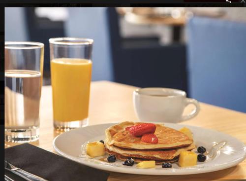 a plate of pancakes with fruit and a cup of orange juice at Country Inn & Suites by Radisson, Fort Worth, TX in Fort Worth