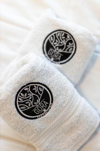 two towels with black and white logos on them at Gora Apartments 3 in Vrdnik