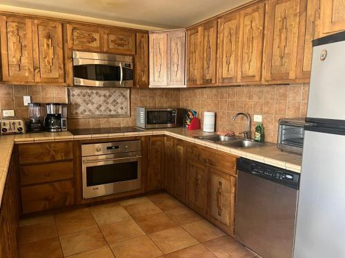 Una cocina con gabinetes de madera y electrodomésticos de acero inoxidable. en Casa Cupulas, en Puerto Peñasco