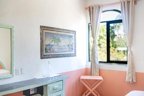 a room with a painting on the wall and a window at Hotel Flor de Maria in Puerto Escondido