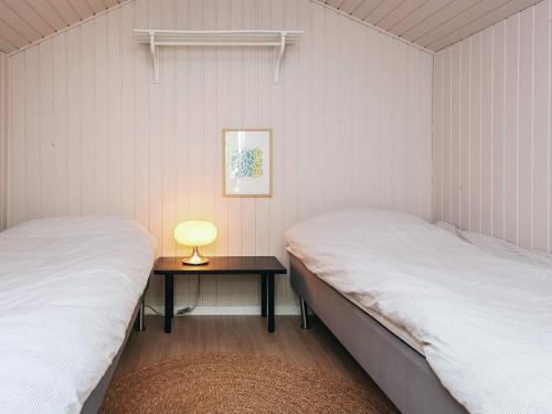 a bedroom with two beds and a table with a lamp at 6 person holiday home in Grenaa in Grenå