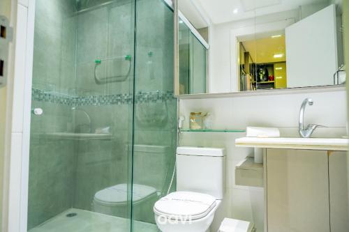 a bathroom with a toilet and a glass shower at Apt. Beira Mar em Cotovelo In Mare 137 - QAVI in Granja Beira Mar