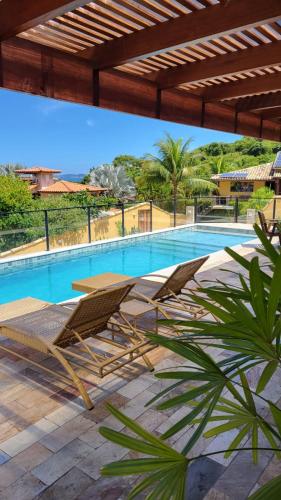 a swimming pool with two lounge chairs next to it at Pousada Búzios Garden in Búzios