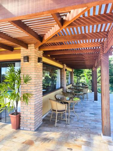 a patio with tables and chairs under a wooden pergola at Pousada Búzios Garden in Búzios