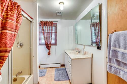 a bathroom with a sink and a mirror and a tub at Lakefront Group Getaway with Dock in Baldwin! in Baldwin
