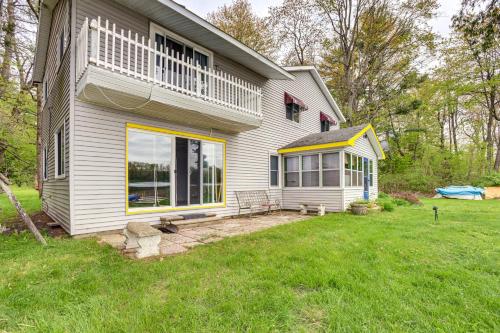 a white house with a large window and a yard at Lakefront Group Getaway with Dock in Baldwin! in Baldwin