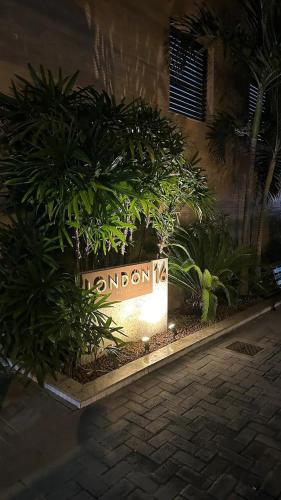 a sign in front of a building with plants at Apart Praia de Icaraí London, Vista Cristo and MAC in Niterói