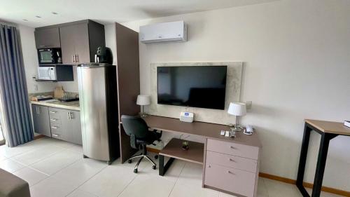 a kitchen with a desk and a television on the wall at Apart Praia de Icaraí London, Vista Cristo and MAC in Niterói