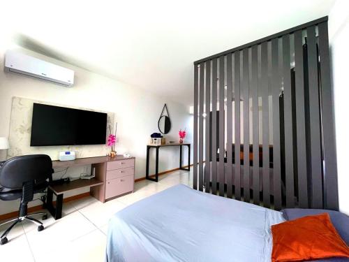 a bedroom with a bed and a desk and a television at Apart Praia de Icaraí London, Vista Cristo and MAC in Niterói
