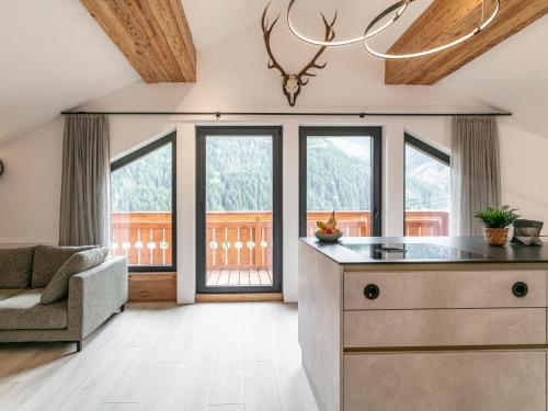 a kitchen with large windows and a couch at Alpenlodge Pettneu Lodge 1 in Pettneu am Arlberg