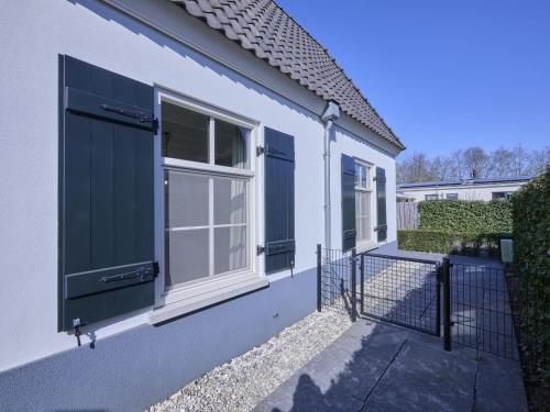 a white house with blue doors and a gate at t Kaatsheuveltje 5 in Sprang-Capelle