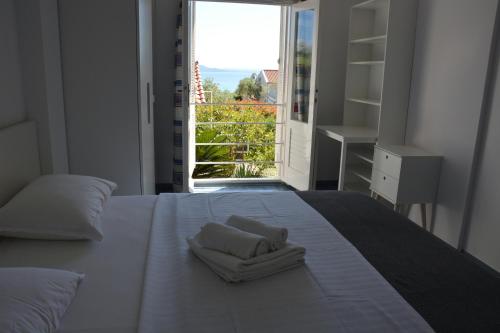 a bedroom with a white bed with a large window at Sunny Cottage in Petrcane