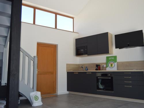 une cuisine avec des armoires noires et un comptoir dans l'établissement Maison rénovée en Berry : terrasse, jardin privé, proche Châteauroux et nature - FR-1-591-164, à Saint-Maur