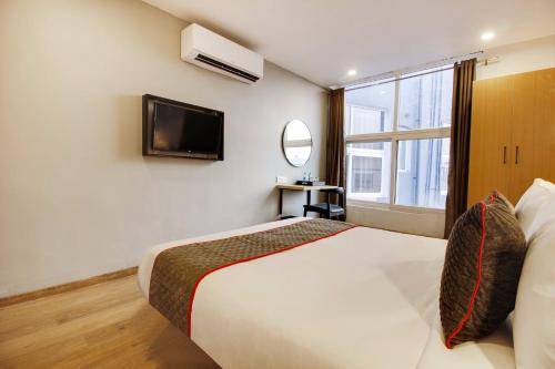 a bedroom with a bed and a tv and a window at Super townhouse moosapet Rcc Prime in Hyderabad