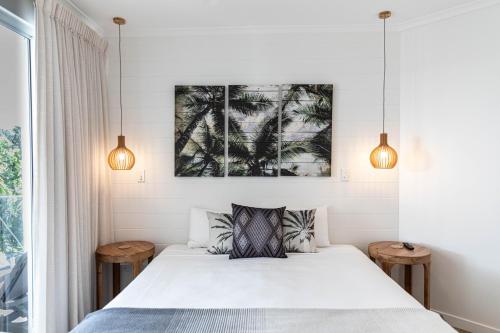 a bedroom with a white bed with two tables at Beaches Holiday Apartments - Official Onsite Reception & Check In in Port Douglas