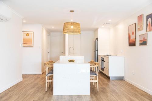 a kitchen with white walls and a white island with chairs at Beaches Holiday Apartments - Official Onsite Reception & Check In in Port Douglas