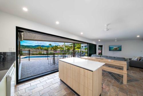 a kitchen and living room with a view of a patio at Day Dreaming - Mazlin House in Airlie Beach