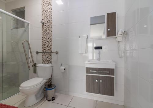 een witte badkamer met toilet en douche bij Pousada Amanhecer do Sul in Penha