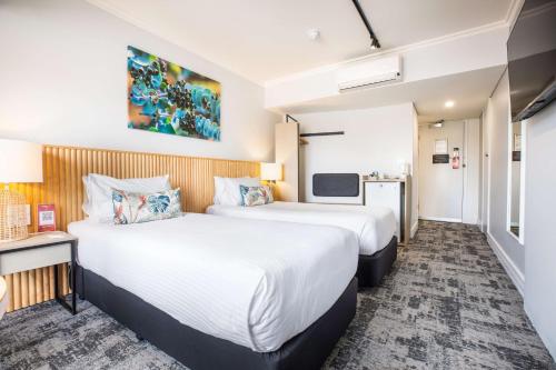 a hotel room with two beds and a television at Nightcap at Hotel Victor in Victor Harbor