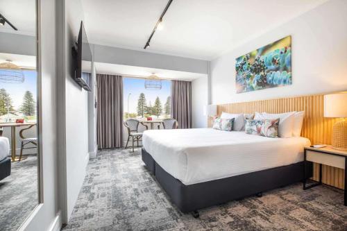 a hotel room with a large bed and a table at Nightcap at Hotel Victor in Victor Harbor