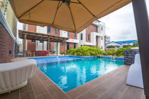 una piscina con un ombrellone accanto a un edificio di Accra airport/pool a Accra