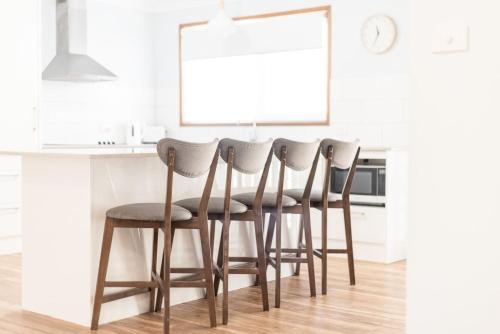 a kitchen with a row of chairs at a counter at Waratah in Iluka