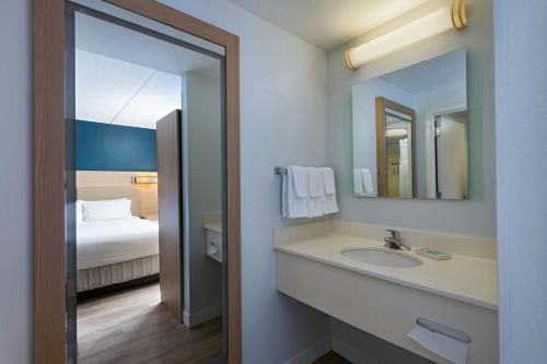 a bathroom with a sink and a bed and a mirror at SpringHill Suites by Marriott Pittsburgh Washington in Washington