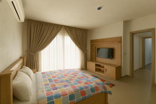a bedroom with a bed and a tv and a window at Nest apartments in Lekki