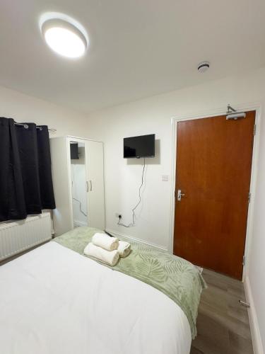 a bedroom with a large white bed with towels on it at Heathrow Lodge BnB in Harmondsworth
