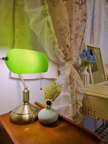 a green lamp on a desk with flowers and a piano at Iriya House 上野 浅草すぐの一軒家貸切ステイ in Tokyo