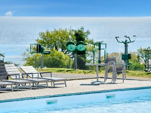 a pool with tables and chairs next to the water at 5 person holiday home on a holiday park in Gudhjem in Gudhjem