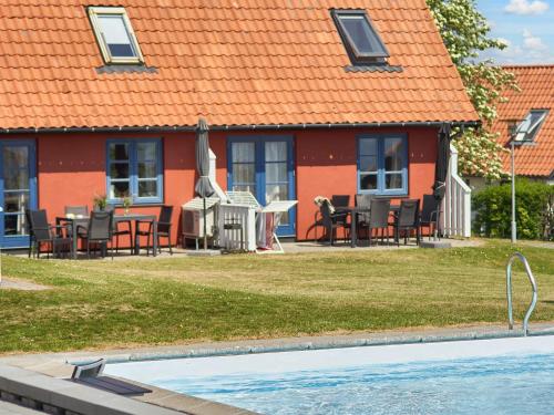 a house with an orange roof and a swimming pool at 5 person holiday home on a holiday park in Gudhjem in Gudhjem