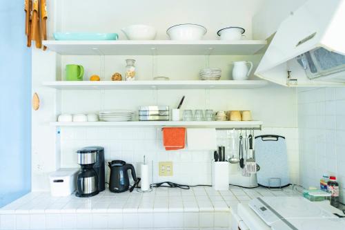 a kitchen with white tiled walls and white shelves at Surf Stay ITOSHIMA in Itoshima