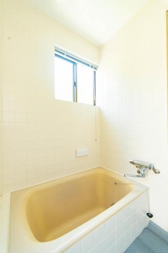 a bath tub in a bathroom with a window at Surf Stay ITOSHIMA in Itoshima