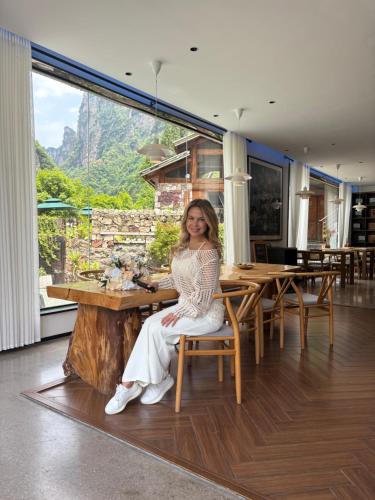a woman sitting at a table in a restaurant at Pandora Vista Retreat in Zhangjiajie