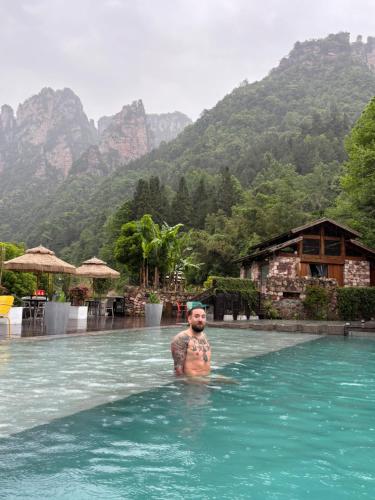 a man standing in the water in a swimming pool at Pandora Vista Retreat in Zhangjiajie
