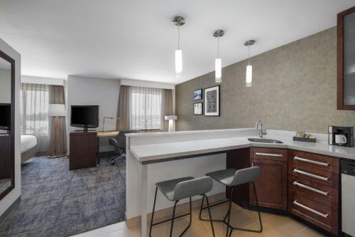 a kitchen with a sink and a living room at Residence Inn by Marriott Champaign in Champaign