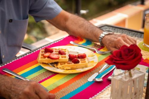 a man standing at a table with a plate of waffles at Serendipity Hospedaje Boutique in Guatapé